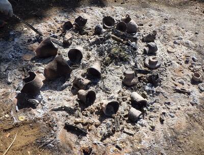 炭の中で土器を転がす様子