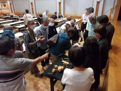 写真：麦わら細工に群がる受講者たち